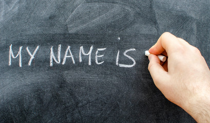 Teacher writing his name on blackboard