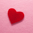 Felt red heart on pink background.