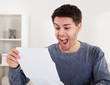 © Andrey Popov - Exultant young man cheering good news