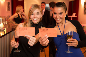 Two women presenting theatre or movie tickets