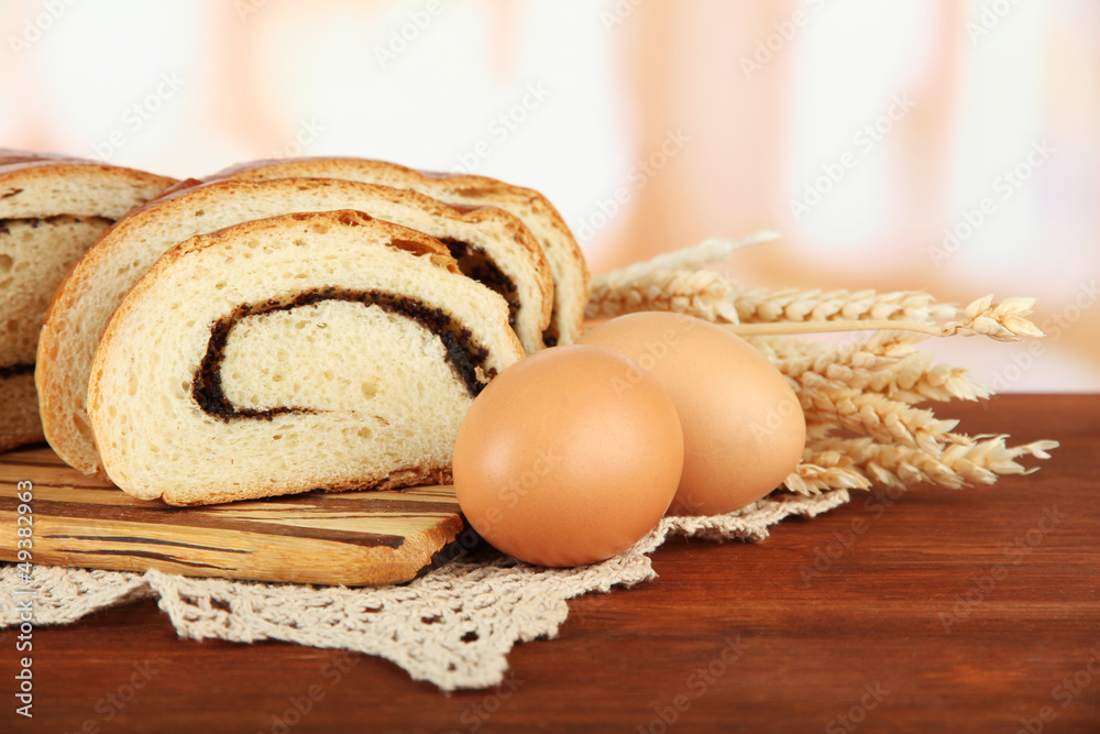Loaf with poppy seed on cutting board, on bright background