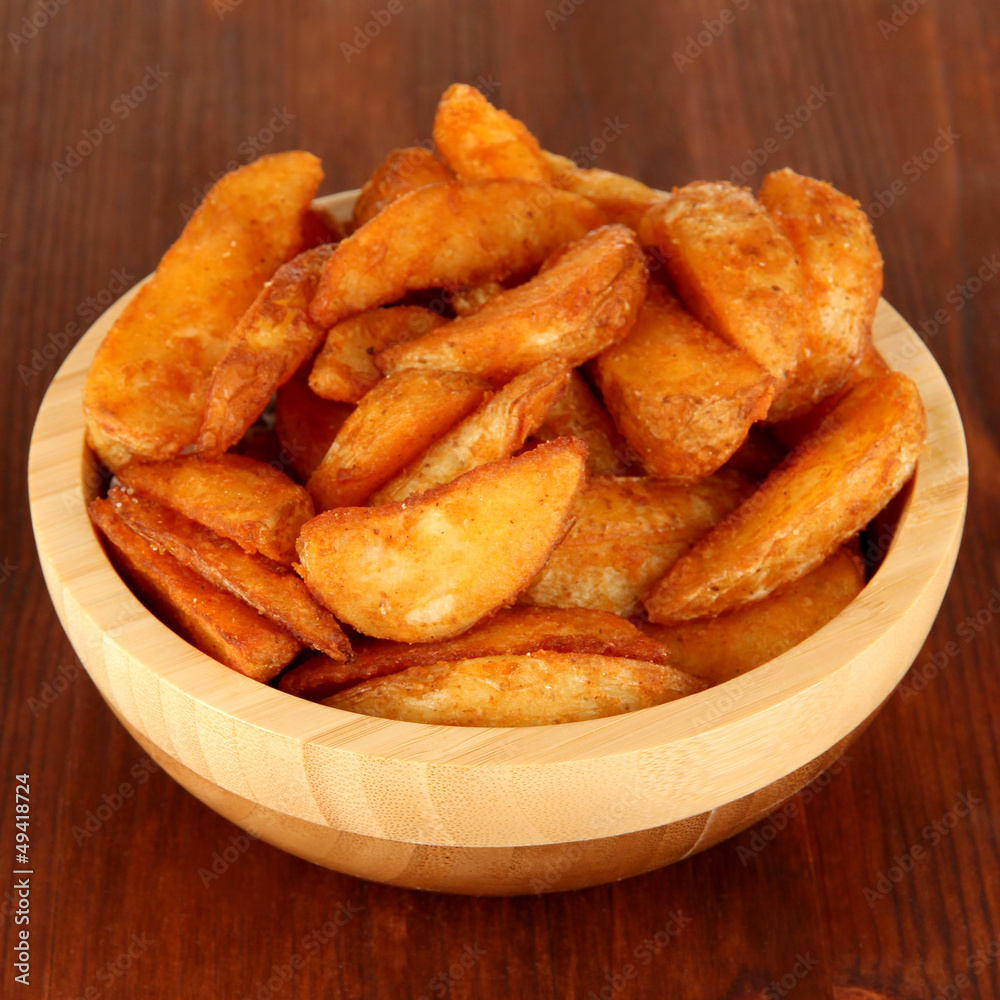 Appetizing village potatoes in bowl on wooden table close-up