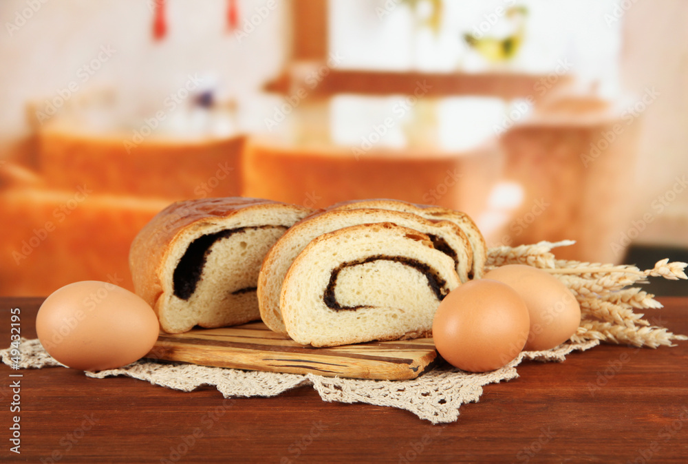 Loaf with poppy seed on cutting board, on bright background