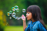 Fototapeta Nowy Jork - Asian little girl is blowing a soap bubbles