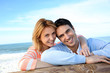 © goodluz - Happy couple leaning on a fence by the sea