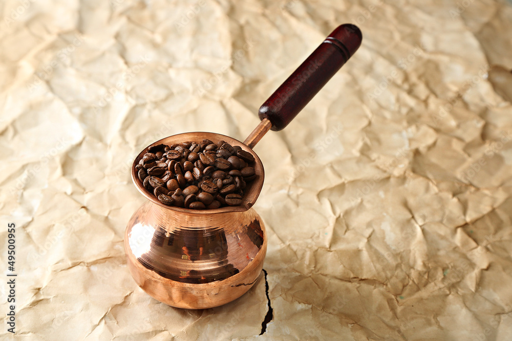 Coffee pot with coffee beans on beige background
