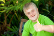 © karelnoppe - Cute handicapped boy showing thumbs up outdoors.