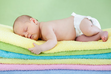 Fototapete - cute baby girl  sleeping on colourful towels