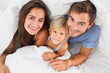 © WavebreakmediaMicro - Family smiling under the duvet on the bed