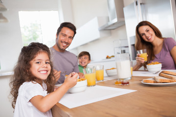 Family smiling at the camera at breakfast