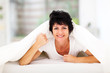 © michaeljung - fun middle aged woman lying under duvet on bed