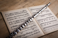 Silver Flute On An Ancient Music Score Background