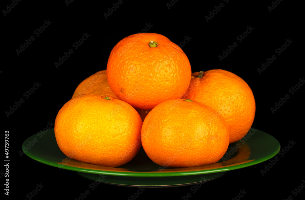 Tasty mandarines  on color plate isolated on black