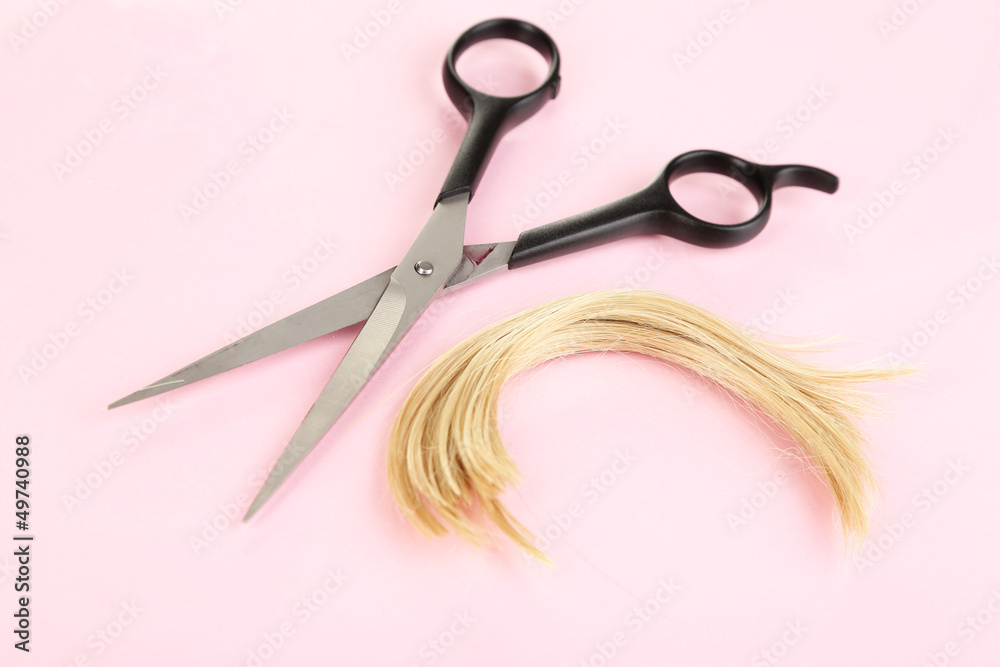 Pieces of hair cut with scissors on pink background