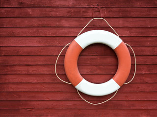 Red and white life buoy hanging on the side of a wooden ship