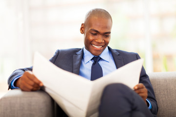 Wall Mural - handsome african corporate worker reading newspaper in office