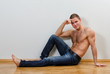 © M-Production - Handsome guy in jeans with bare torso sitting on the floor