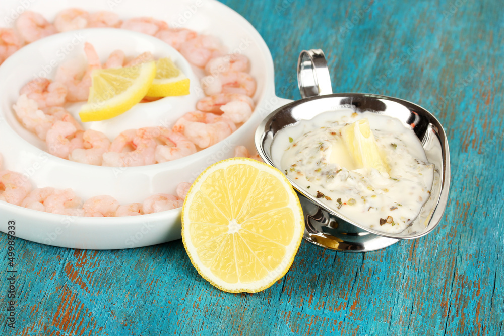 Shrimps with lemon on plate on blue wooden table close-up