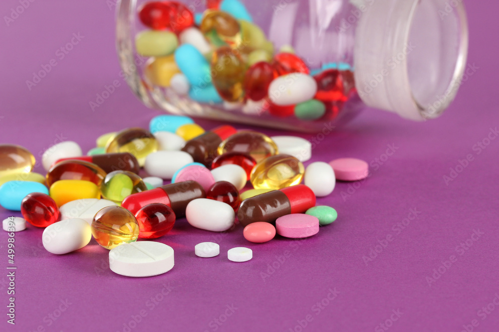 Assortment of pills, tablets and capsules on purple background