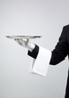 Waiter holding empty silver tray over gray background