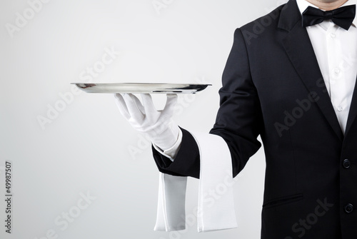 Fototapeta dla dzieci Waiter holding empty silver tray over gray background