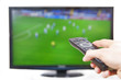 Hand pointing TV with remote controller sports in background