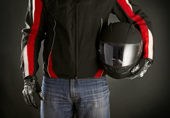 Fotobehang - biker with helmet in his hands. dark background