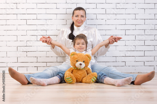 Mother, daughter and toy sitting against the wall Poster