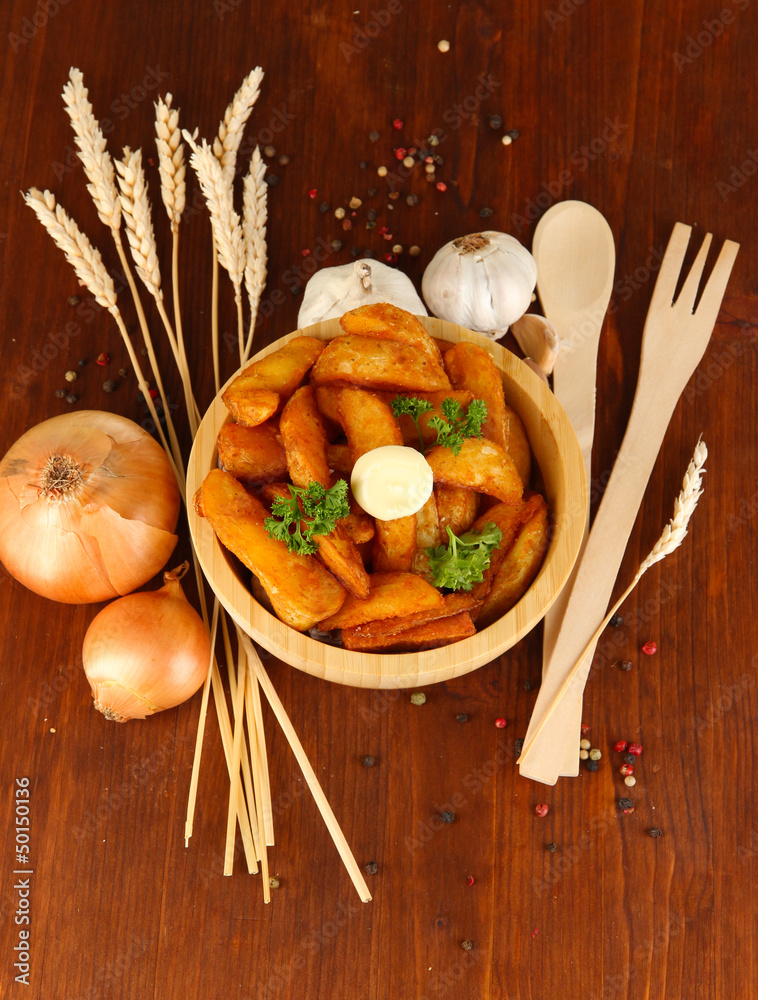 Appetizing village potatoes in bowl on wooden table close-up