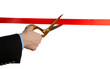 Man's hand cutting red ribbon with pair of scissors isolated