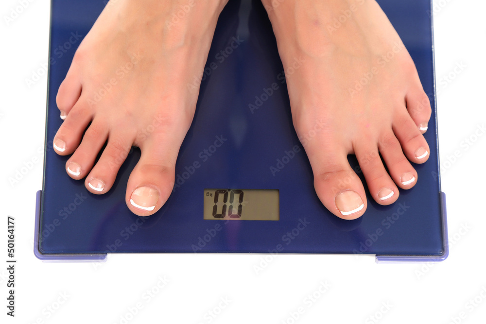 Bare female feet standing on scale isolated on white