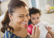 © JGI/Jamie Grill/Blend Images - Mixed race mother holding baby and eating apple