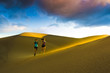 © Michael DeYoung/Blend Images - Hispanic couple running on sand dune