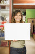 © GM Visuals/Blend Images - Hispanic woman holding blank sign in store