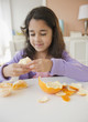 © JGI/Jamie Grill/Blend Images - Mixed race girl peeling an orange
