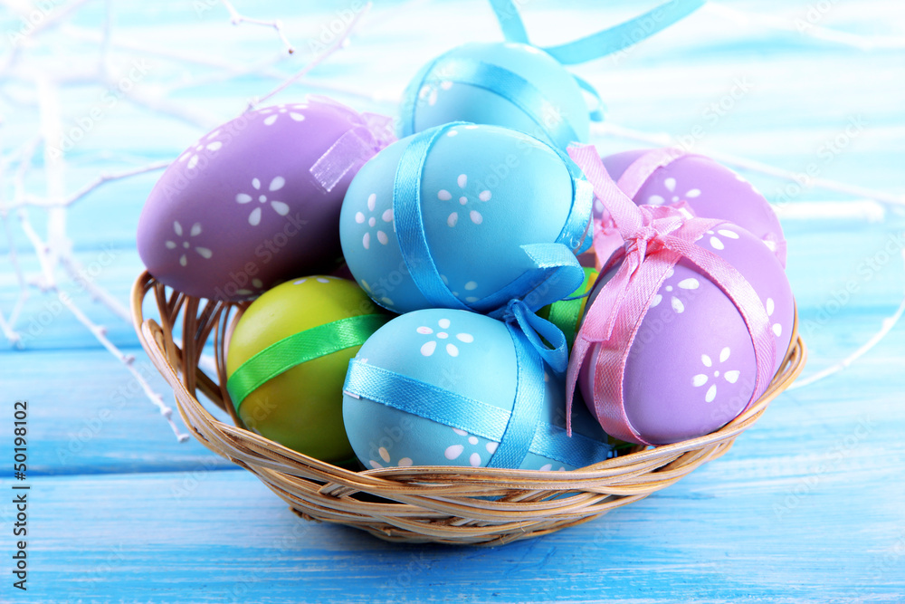 Easter eggs in basket, on blue wooden background