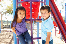 Boy And Girl On Climbing Frame In Park