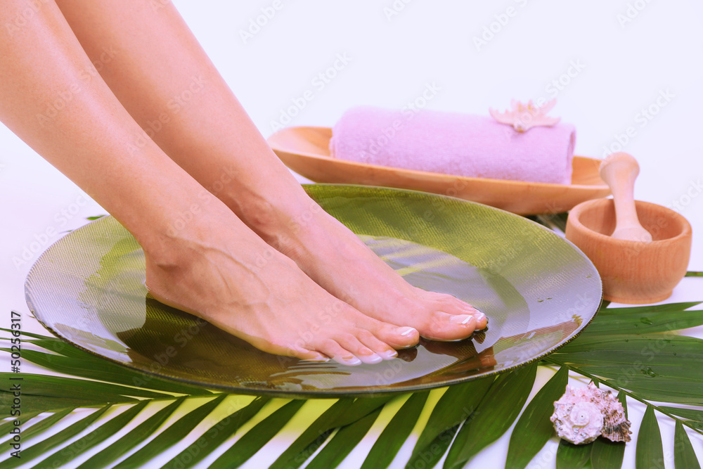 Female feet in spa bowl with water, isolated on white