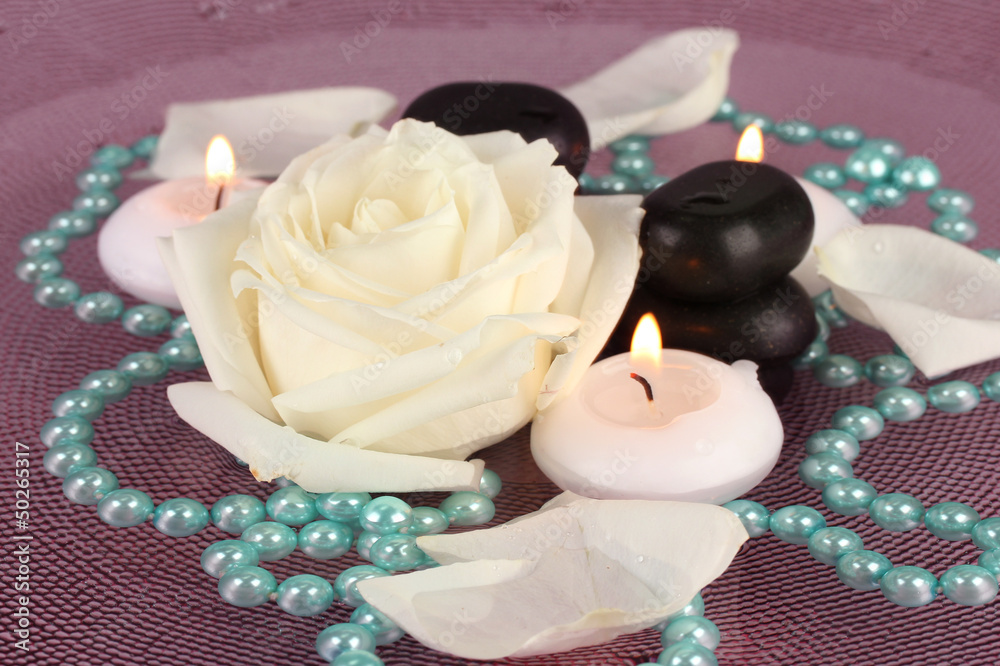 spa stones with flower and candles in water on plate