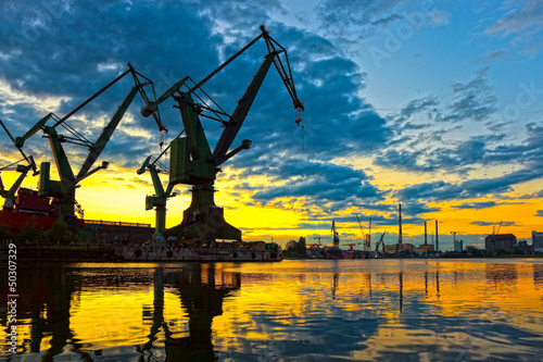 Fototapeta na wymiar Monumental Cranes at sunset in Shipyard.