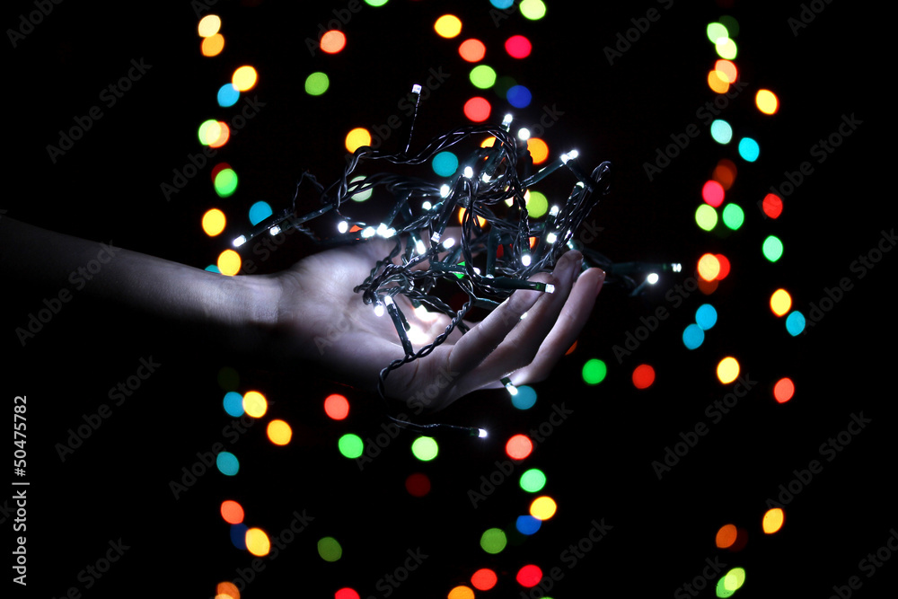 Christmas lights in hand on blur lights background