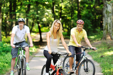 Portrait of attractive young woman on bicycle and two men in blu