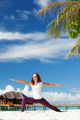 Wall Mural - Pretty woman doing yoga exercises on the beach