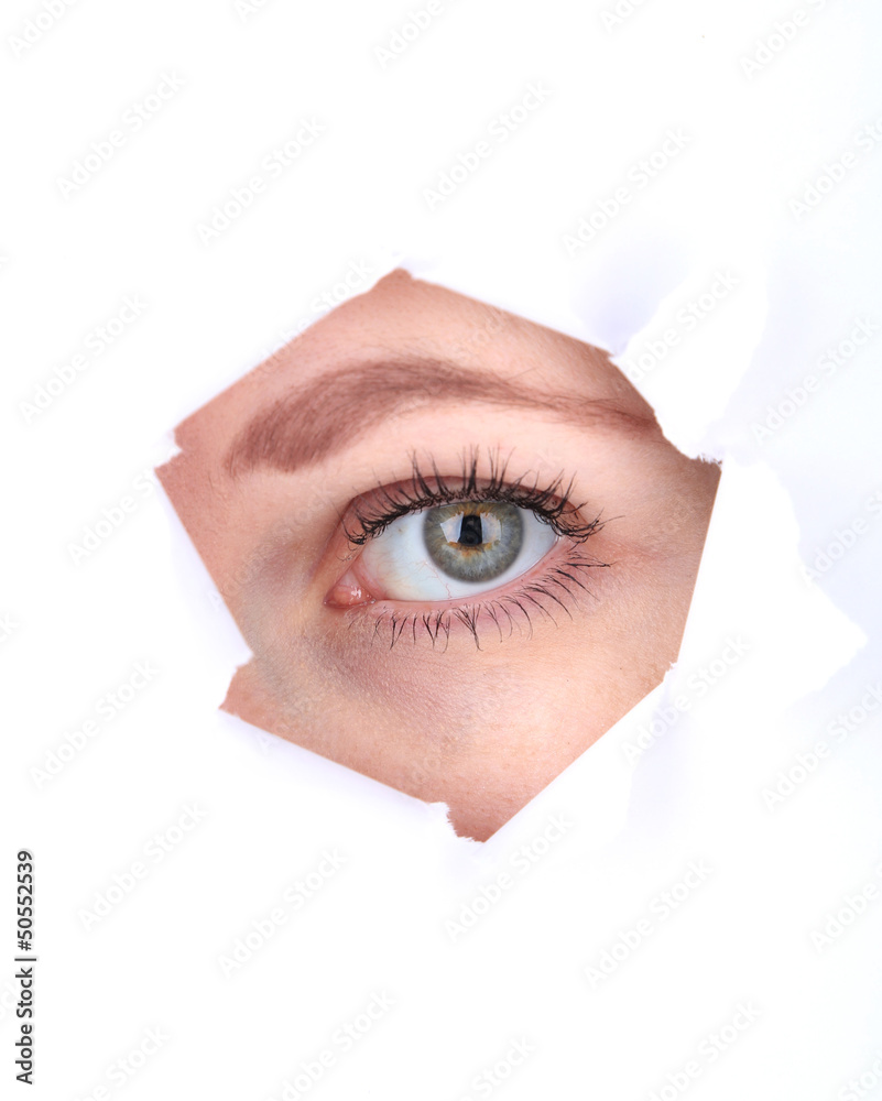 Female eye looking through hole in sheet of paper