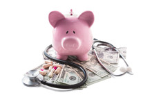 Piggy Bank Tablets Stethoscope Resting On Pile Of Dollars