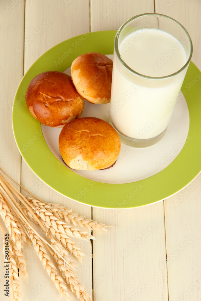 Bread rolls and glass of milk on wooden table