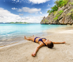 Poster - Young beautiful woman is relaxing on sand by the sea