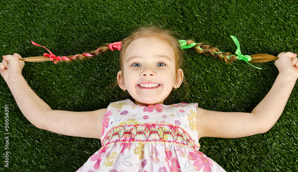 Smiling happy little girl lying on grass Stock Photo | Adobe Stock
