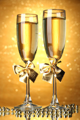 Two glasses of champagne on bright background with lights