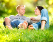 Park. Young Couple Lying on Grass Outdoor
